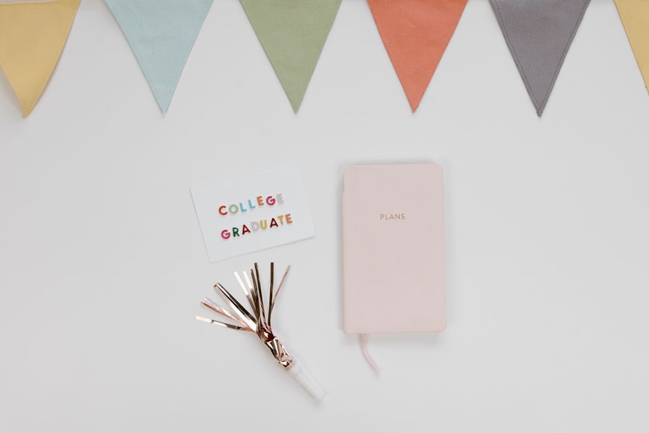 Flat lay of a graduation card, planner, and decorations for a college celebration.
